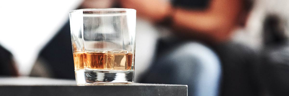 Glass with whiskey on table